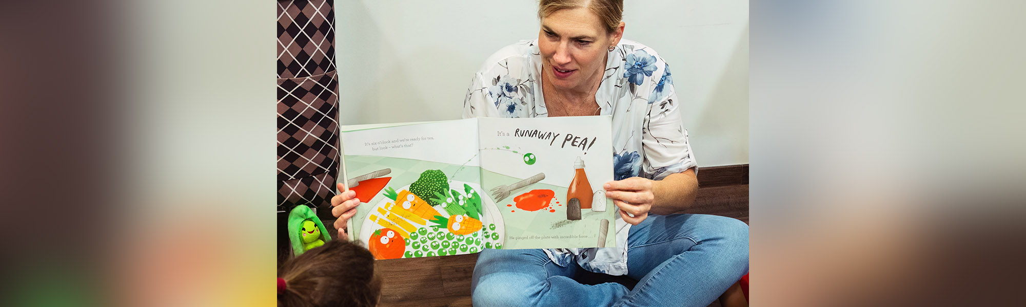 An adult showing a reading book to a child