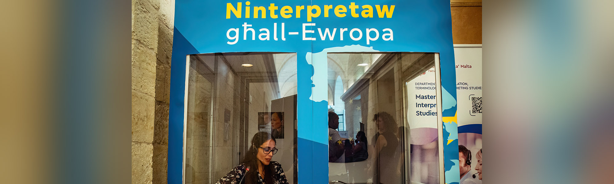 A person at an interpreting booth. Ninterpretaw għall-Ewropa banner